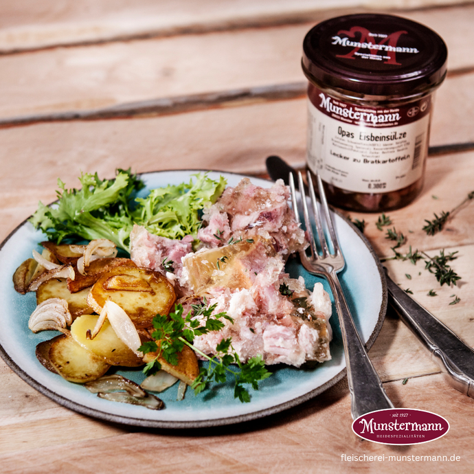 Eisbeinsülze auf einem Teller mit Bratkartoffeln und Salat